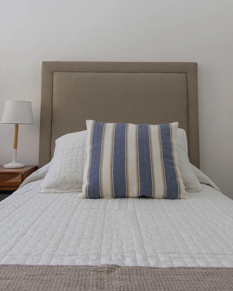 Cubrecama Petra sobre una cama con almohadón a rayas azules
