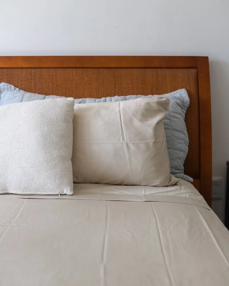 Cama tendida con sábanas de algodón satén beige
